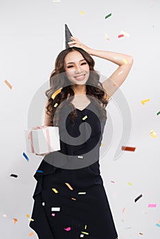 Portrait of asian woman in birthday hat and confetti on white ba