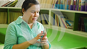 Portrait of Asian woman with blindness disability wearing earphones enjoy using smart phone with voice accessibility for persons