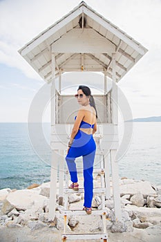 Portrait Asian woman in a blue suit  sitting at a white guardhouse in front of a sea and sky background
