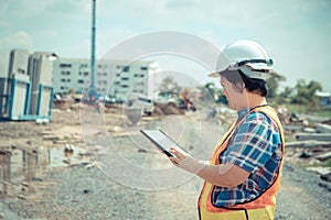 Portrait of Asian woman construction engineer worker with helmet on head using tablet while standing on construction site. buildin