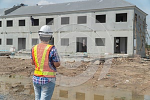 Portrait of Asian woman construction engineer worker with helmet on head using tablet while standing on construction site. buildin