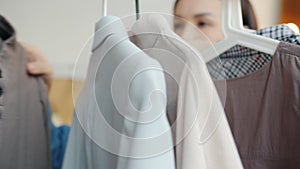 Portrait of Asian woman dressmaker checking clothes on rails hangers in modern showroom