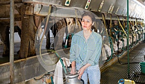 Portrait of a asian woman on a farm, passing by a milking machine, holding a milk flask