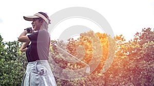 Portrait of a Asian woman golfer in black T-shirt with a golf club on a background of golf courses