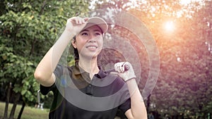 Portrait of a Asian woman golfer in black T-shirt with a golf club on a background of golf courses