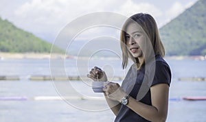 Portrait Asian woman holding a coffee cup in hand and drinking  Background Water blur and the mountains in the dam