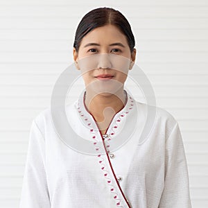 Portrait of Asian woman with little make-up in native Thai style massage shop employee uniform standng  and pose to camera with