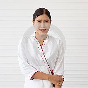 Portrait of Asian woman with little make-up in native Thai style massage shop employee uniform standng  and pose to camera with