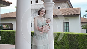Portrait of asian woman mother holding baby infant on balcony terrace at luxury home looking away the morning view. happy smile 30