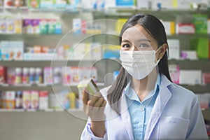 Portrait of asian woman pharmacist wearing a surgical mask in a modern pharmacy drugstore, covid-19 and pandemic concept