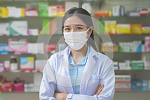 Portrait of asian woman pharmacist wearing a surgical mask in a modern pharmacy drugstore, covid-19 and pandemic concept