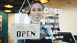 Portrait of Asian woman restaurant or coffee shop owner smile, hanging open sign post