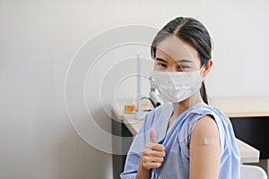 Portrait asian woman showing arm with bandage after getting flu or vaccine