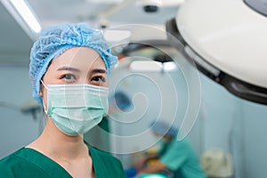 Portrait of Asian woman surgeon with medical mask standing in operation theater at a hospital. Team of Professional surgeons.