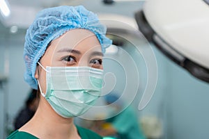Portrait of Asian woman surgeon with medical mask standing in operation theater at a hospital. Team of Professional surgeons.