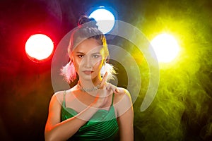 Portrait of Asian Woman Transgender wear Beautiful Green Evening long Gown, smile to camera over Back Lights colorful yellow, red