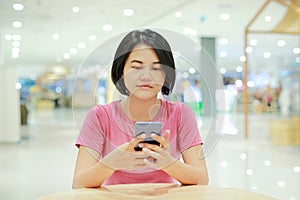 Portrait of Asian woman using smartphone on table at department store