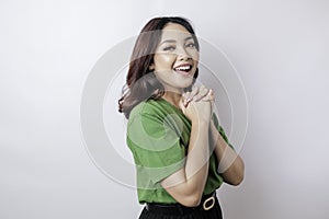 A portrait of Asian woman wearing green t-shirt is praying for success isolated by white background