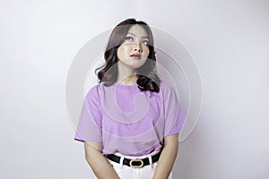 A portrait of an Asian woman wearing a lilac purple t-shirt isolated by white background looks depressed