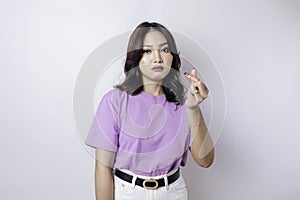 A portrait of an Asian woman wearing a lilac purple t-shirt isolated by white background looks depressed