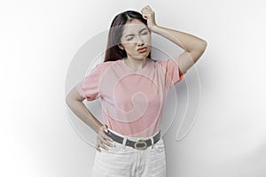 A portrait of an Asian woman wearing a pink t-shirt isolated by white background looks depressed