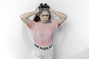 A portrait of an Asian woman wearing a pink t-shirt isolated by white background looks depressed