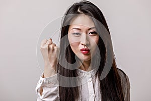 Portrait of asian woman in white shirt showing fist