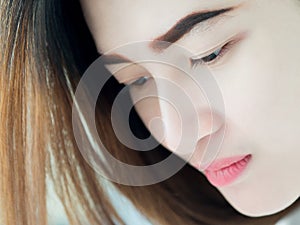 Portrait of Asian woman in white vest, expressing the idea of broken heart and sadness.