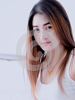 Portrait of Asian woman in white vest, on her bed, expressing the idea of broken heart and sadness. hopeless and await, concept.