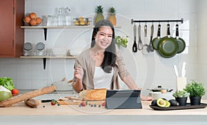 Portrait of Asian young beautiful woman standing in the kitchen and cooking healthy food with bread, fruits and vegetables.