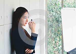 Portrait of Asian young long hair beautiful business woman in navy blue suit thinking in modern office. Future plans, Business con