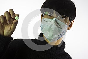 Asian young man in mask, pill in hand. Prevent spread of coronavirus
