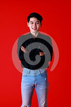 Portrait asian young man standing while folded arms crossed and looking at camera with feel confident and happy with smile on face