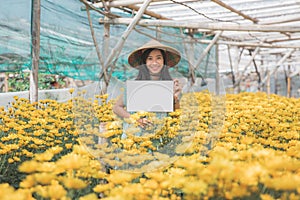 Young woman with blank white board in flower farm