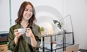 Portrait of Asian young woman holding hot coffee or tea cup in morning while posing