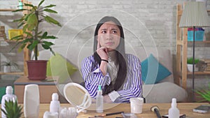 Portrait of an Asian young woman thoughtfully choosing cosmetics