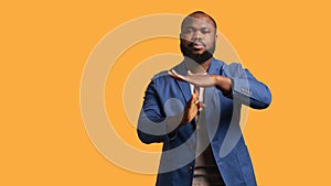 Portrait of assertive man asking for timeout, studio background photo