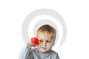 Portrait of an astonished cute little boy holding a red telephone receiver.