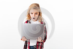 Portrait of an astonished little girl looking at laptop