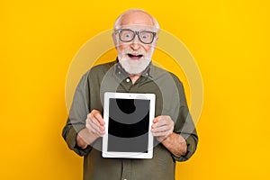 Portrait of astonished person demonstrate empty space tablet display proposition isolated on yellow color background