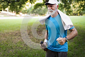 Portrait of athletic mature man after run. Handsome senior man resting after jog at the park