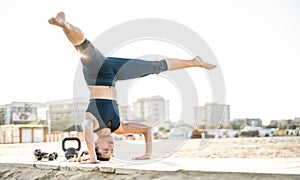 Portrait of athletic woman exercising calisthenic balance move at outdoors beach location - Modern alternative work out