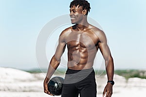 Portrait of athletic workout, African American man, with ball outdoors in nature