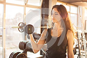 Portrait of athletic young woman training with a weight in the gym.