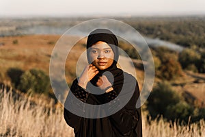 Portrait of attractive african girl in black traditional robe. Salah praying in god. photo