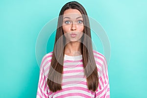 Portrait of attractive amorous girl wearing striped jumper sending air kiss  over vibrant teal turquoise color