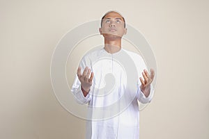 Retrato atractivo asiático hombre en blanco camisas calaveras ora su manos elevado. imagen sobre el 