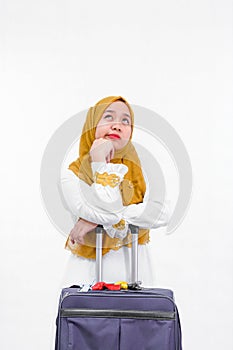Portrait of attractive asian muslim woman on white dress with hijab bring purple suitcase isolated over white background