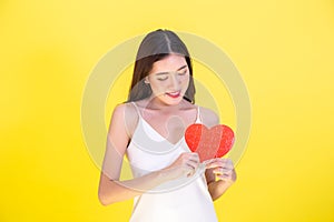 Portrait of attractive Asian smiling woman holding red heart paper jigsaw .