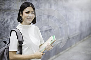 Portrait of attractive asian student girl standing holding books.